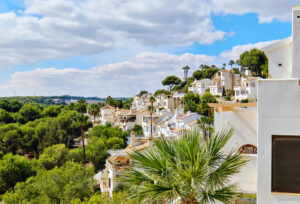 White houses nestled among lush green trees under a partly cloudy sky.